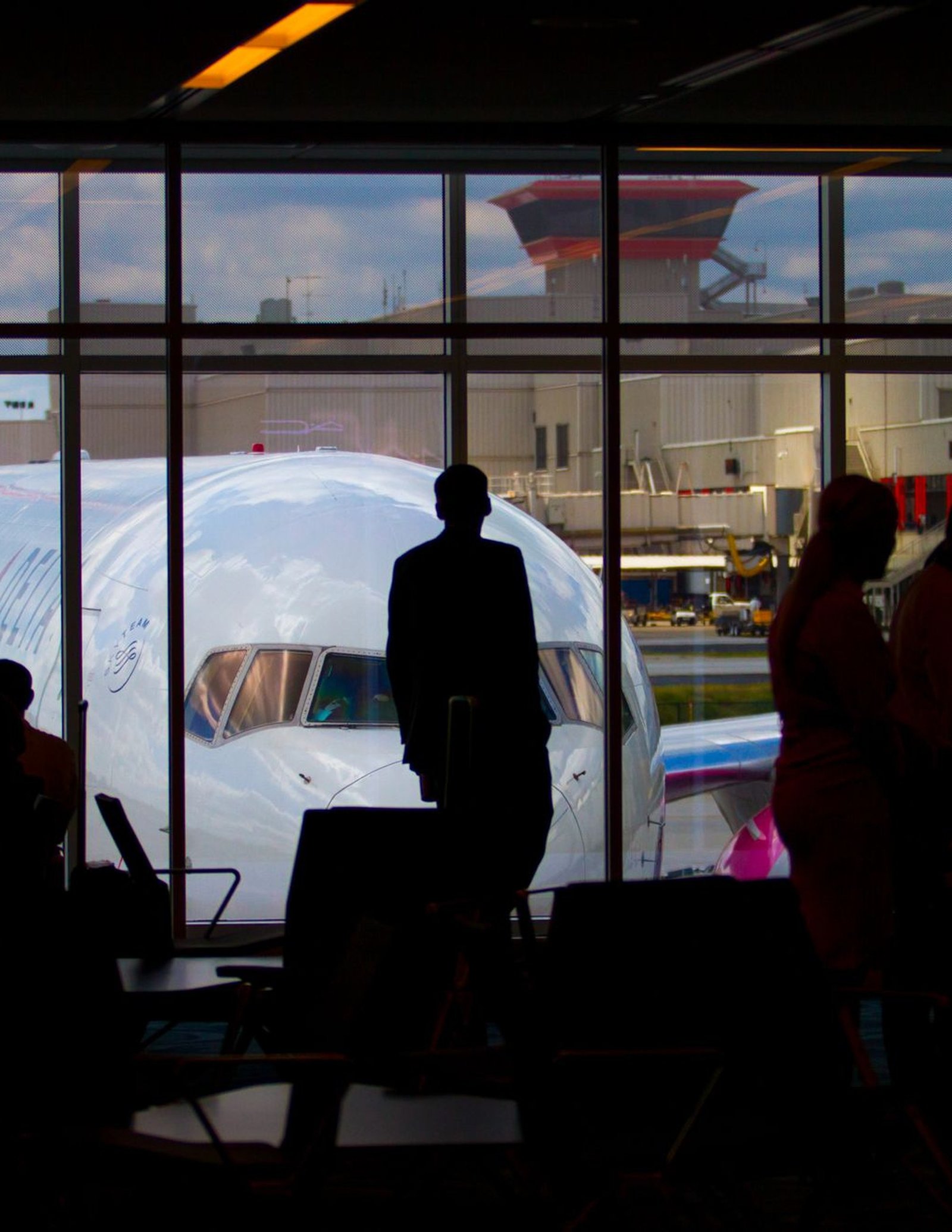 Travelers waiting at a boarding gate as a plane sits outside